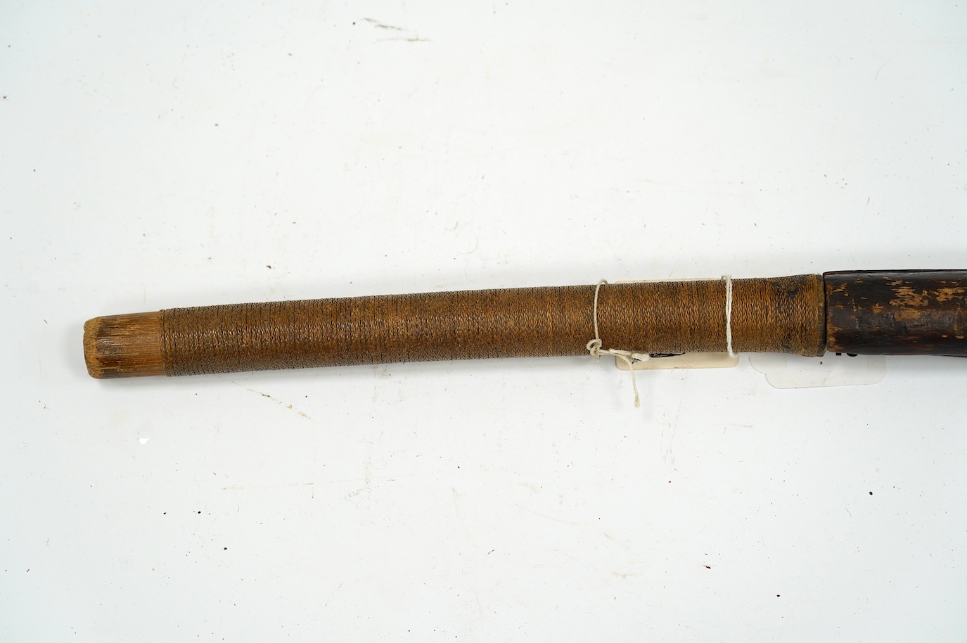 A Burmese sword Dha, curved single edge blade, hilt bound with platted rattan, in its wooden scabbard, blade 60cm. Condition - fair
